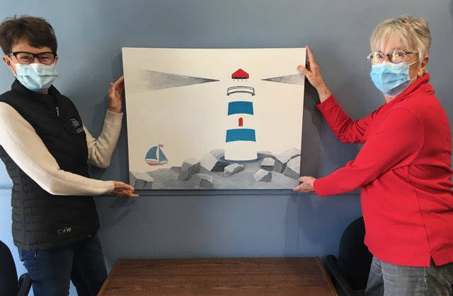 <p>CONTRIBUTED PHOTO</p><p>South Shore Hospice Palliative Care Society board members Marlene Downe (left) and Anne Freeman make preparations to install the painting of the society&#8217;s logo at their new home. The painting was donated by Blue Rocks artist Linda Roe.</p>